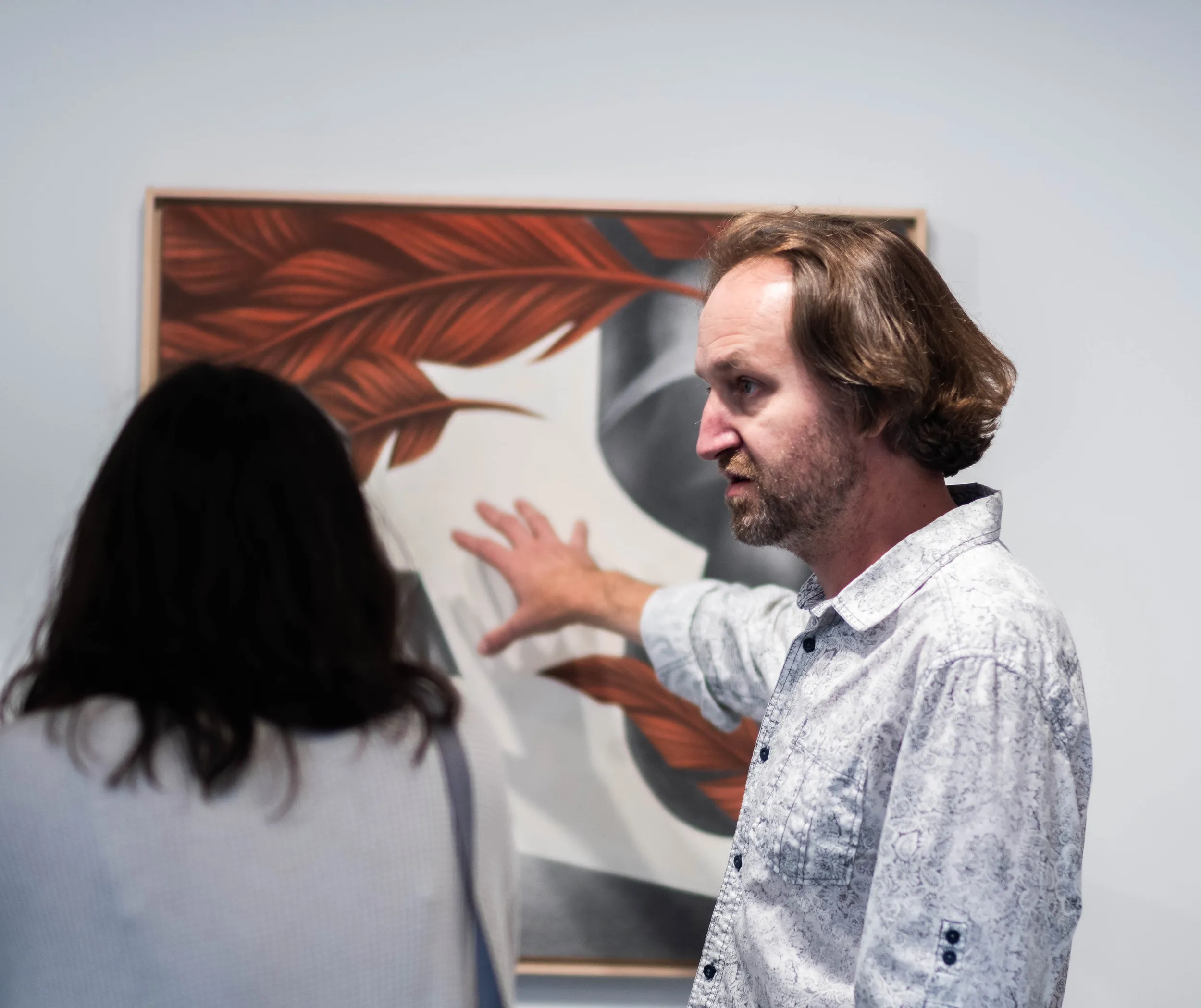 Artist Vladimir Zimakov talking with a visitor in front of his painting