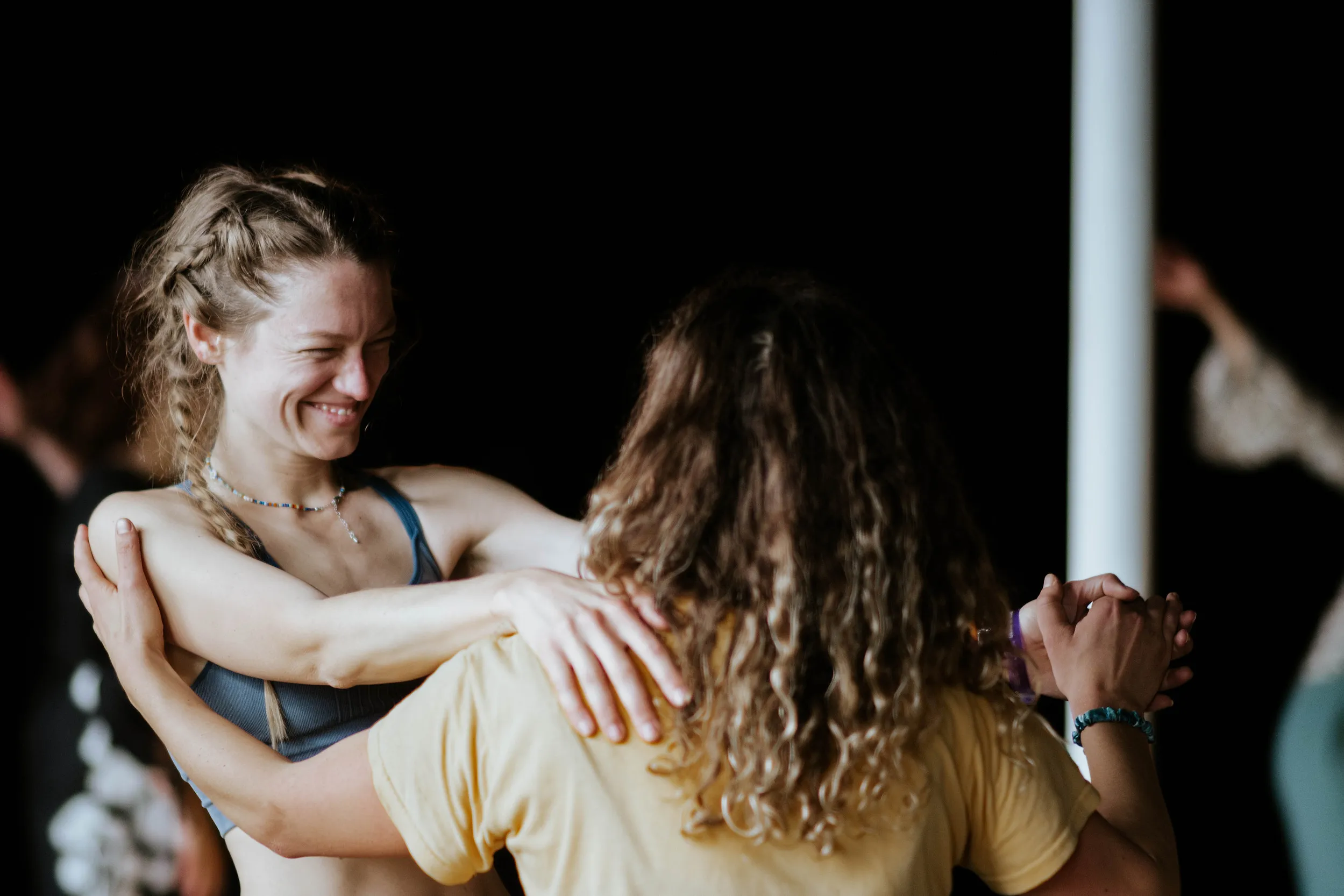 Two dancers embracing and laughing at a 5Rhythms class